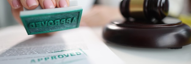 Female hand holding approved stamp judge gavel