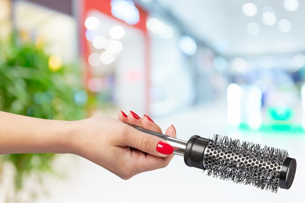 Female hand holding barber comb in cosmetic store