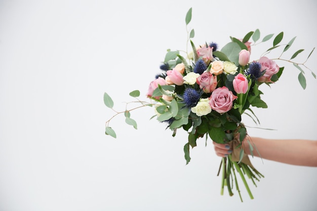 Female hand holding beautiful bouquet on light background