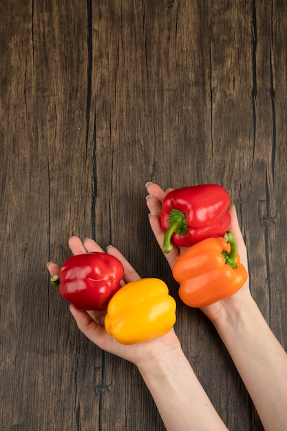 Female hand holding bell pepper on wooden surface