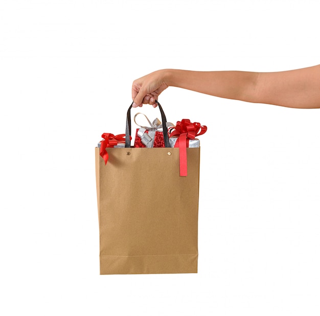 Female hand holding blank brown papaer shopping bags full of gift boxes ornamented