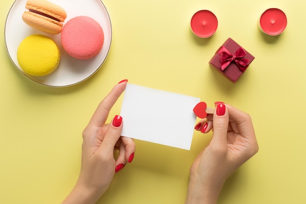 Фото Женская рука держит чистую бумажную карточку на цветном фоне