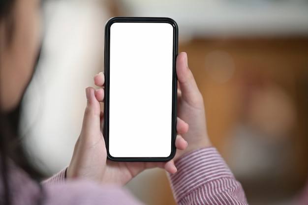  female hand holding blank white screen mobile phone over blurred bokeh background