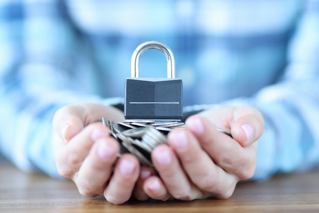 Female hand holding bunch of coins and padlock. safe storage of money concept