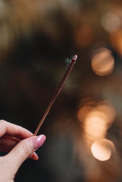 Photo female hand holding burning incense aromatherapy smoke