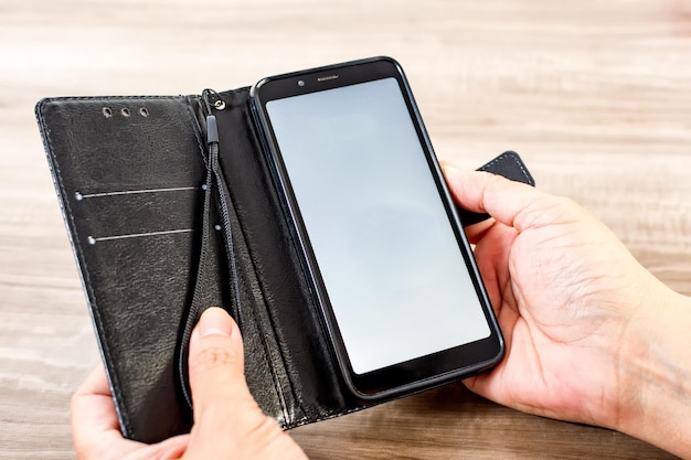 Female hand holding cell phone on wooden table