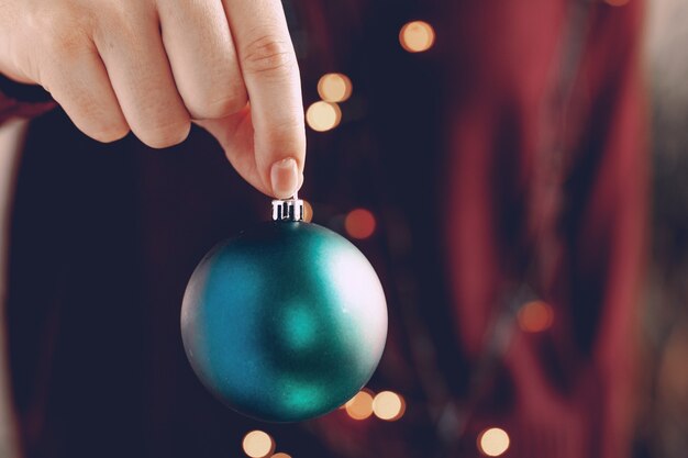 Photo female hand holding a christmas ball close up, festive background