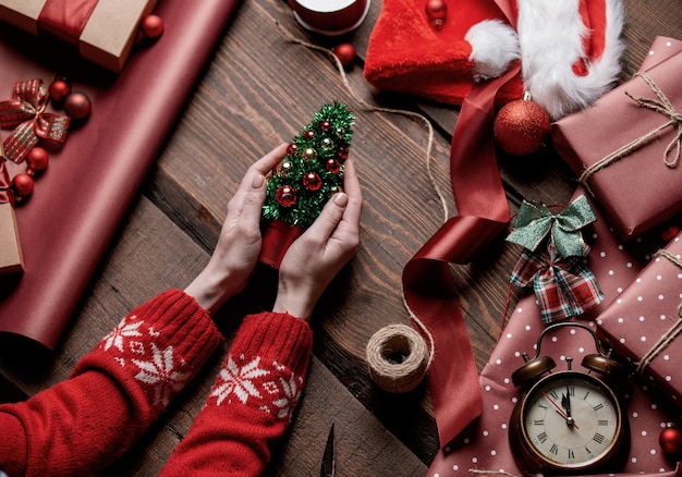 Female hand holding Christmas tree on table with pine branches