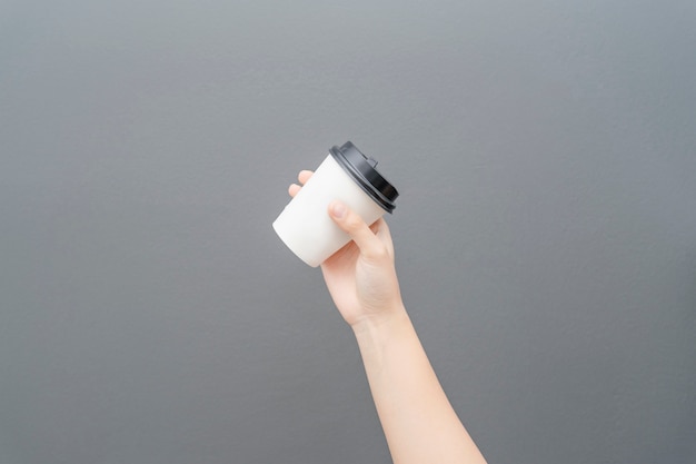 灰色のコーヒー紙コップを持っている女性の手