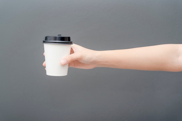 Photo female hand holding a coffee paper cup on gray