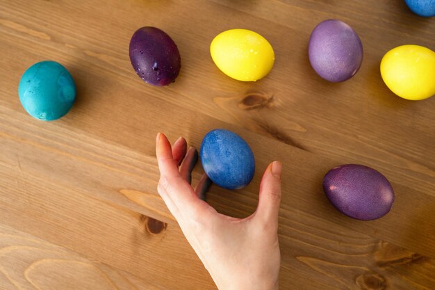 Фото Женская рука, держащая красочные пасхальные яйца на деревянном фоне