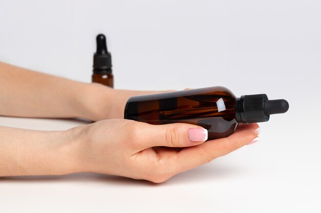 Female hand holding cosmetic bottle on white