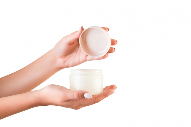 Female hand holding cream bottle of lotion isolated. Girl opening jar cosmetic products