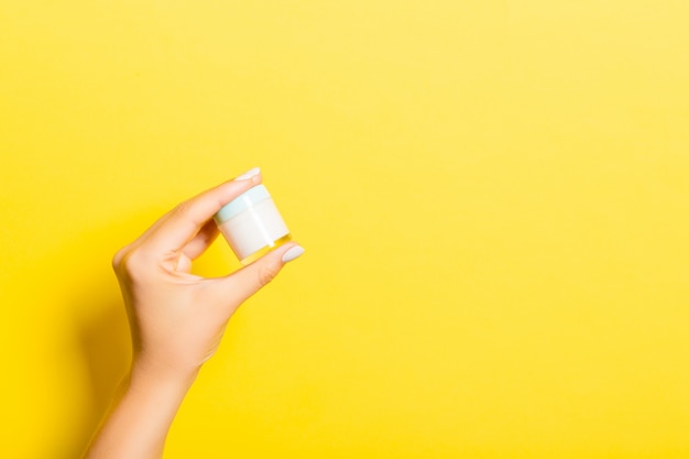 Female hand holding cream bottle of lotion isolated