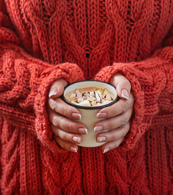 Mano femminile che tiene una tazza di cioccolata calda o di cioccolato con marshmallow