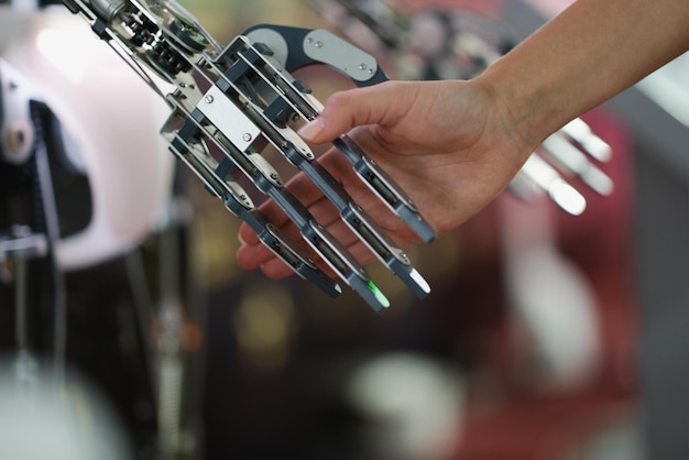 Female hand holding a cyborg metal hand