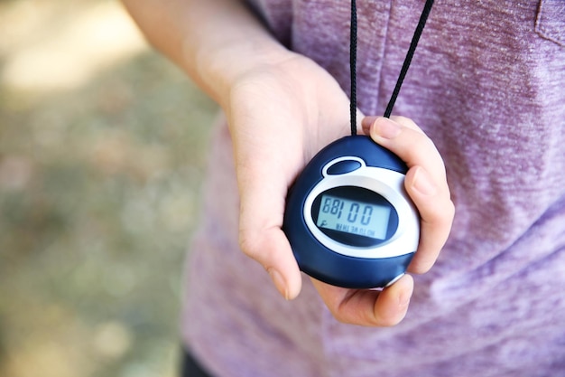 Female hand holding digital stopwatch close up