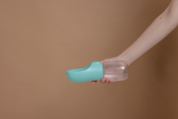 female hand holding a drinking bowl for dogs and animals on a beige background animal care concept