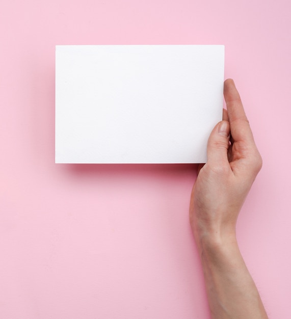 Female hand holding an empty white card or paper note