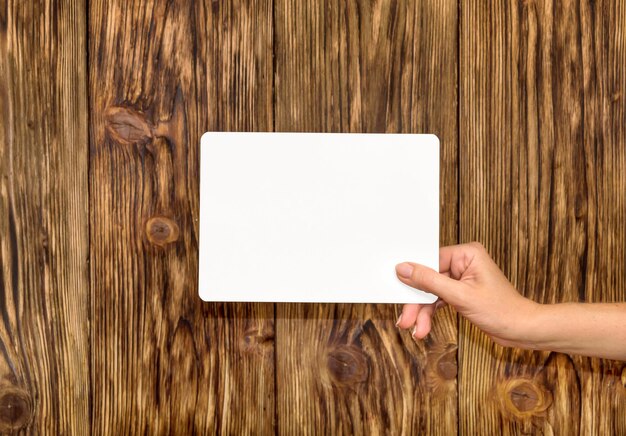 Female hand holding empty white sheets on wooden background