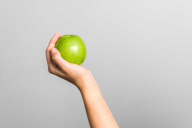 female hand holding green apple