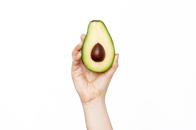 Una mano femminile in possesso di un mezzo avocado isolato su uno sfondo bianco perdita di peso dieta