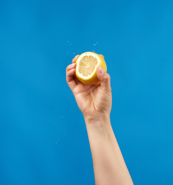 Female hand holding half of a lemon