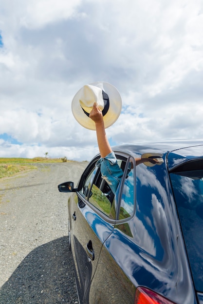 Female hand holding hat out of car window