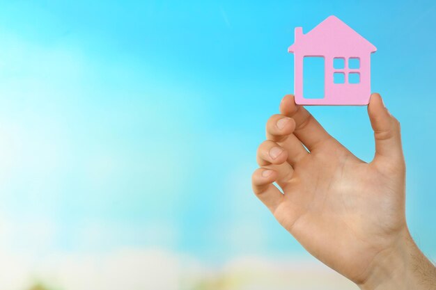 Female hand holding house on turquoise background