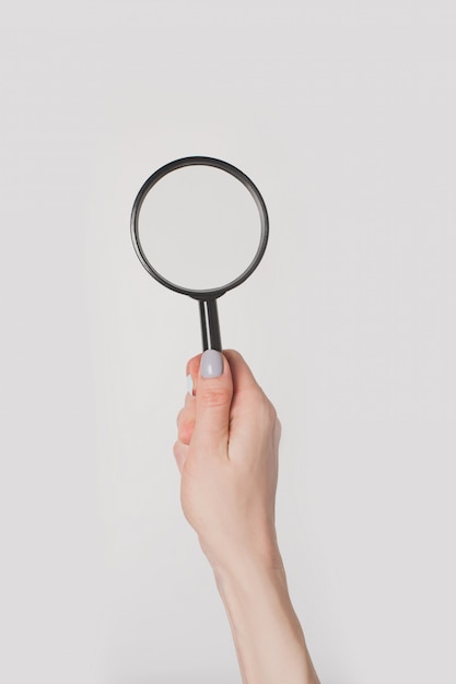 Female hand holding magnifier isolated