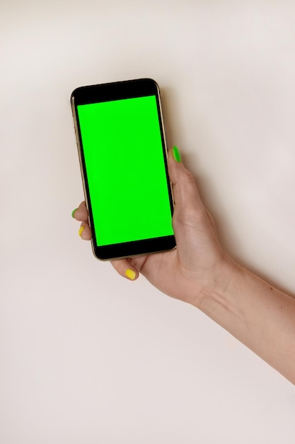 female hand holding a mobile phone with a vertical green screen light table Vertical photography