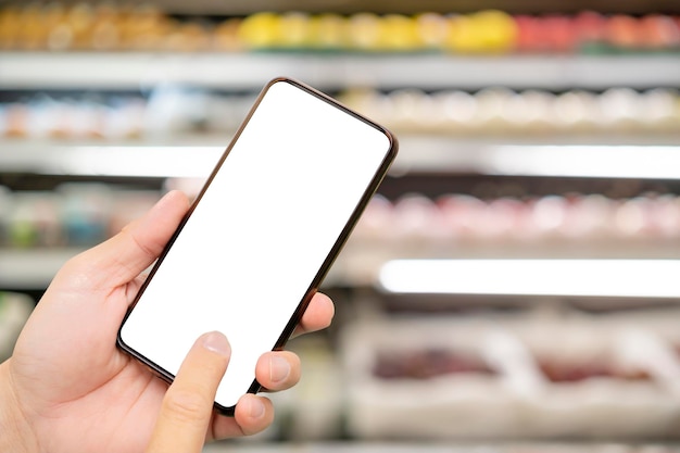 Female hand holding mobile smart phone on Supermarket blur background