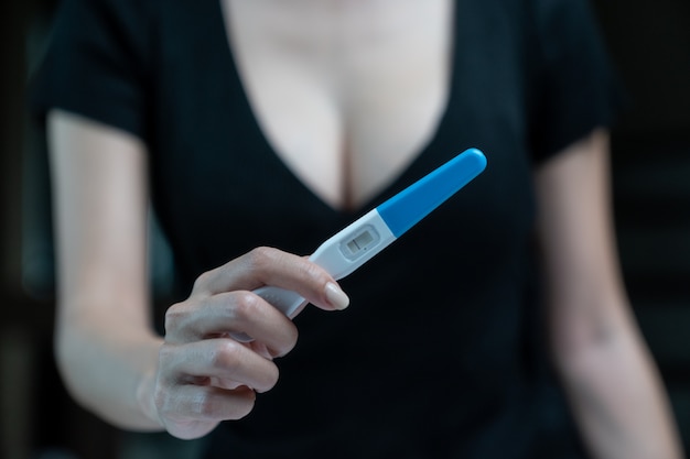 Female hand holding negative pregnancy test, with not pregnant results.