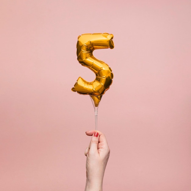 Female hand holding a number birthday anniversary celebration gold balloon