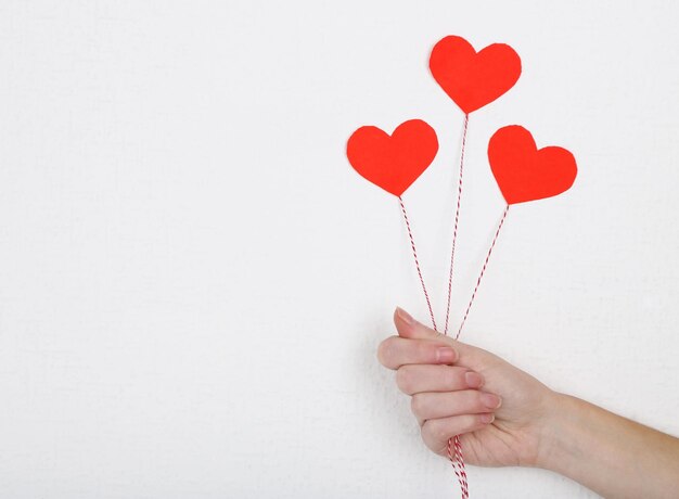 Female hand holding paper balloons, on white wall background