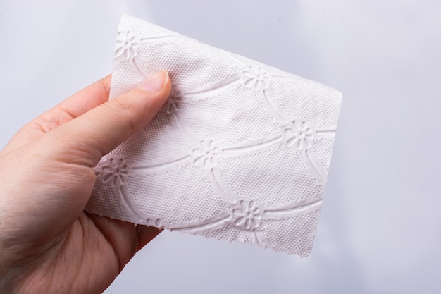 Female hand holding a pece of toilet paper in her hands