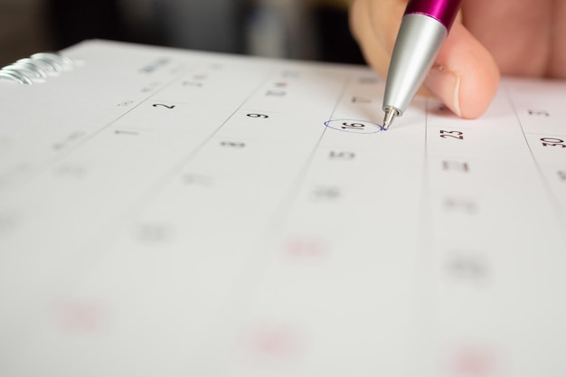 Female hand holding pen circle mark on calendar page