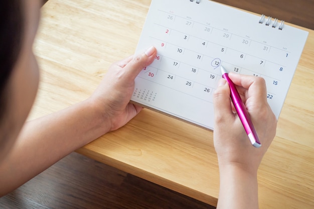 female hand holding pen mark on calendar