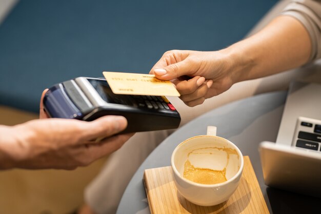 사진 카페에서 카푸치노를 지불하는 동안 웨이터가 개최하는 전자 지불 기계를 통해 플라스틱 카드를 들고 여성 손