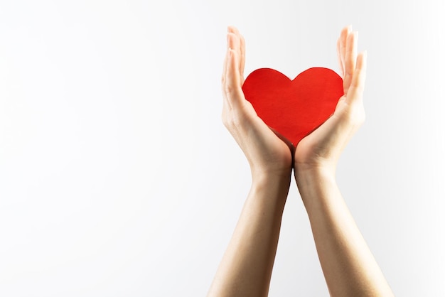 Female hand holding a red heart on a white background. Health care and medicine concept. AIDS awareness.