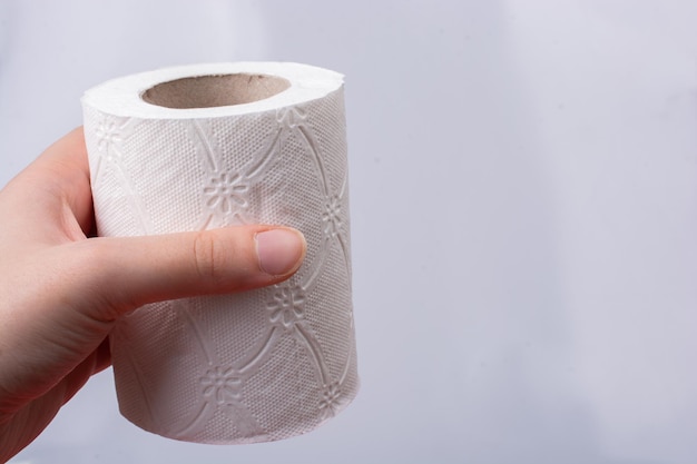 Female hand holding a roll of toilet paper in her hands