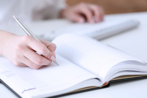 Female hand holding silver pen ready to make note