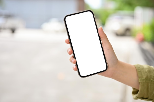 A female hand holding a smartphone mockup over blurred road or street in the background