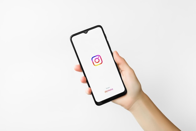 Foto mano femminile che tiene smartphone con il logo dell'app instagram sullo schermo