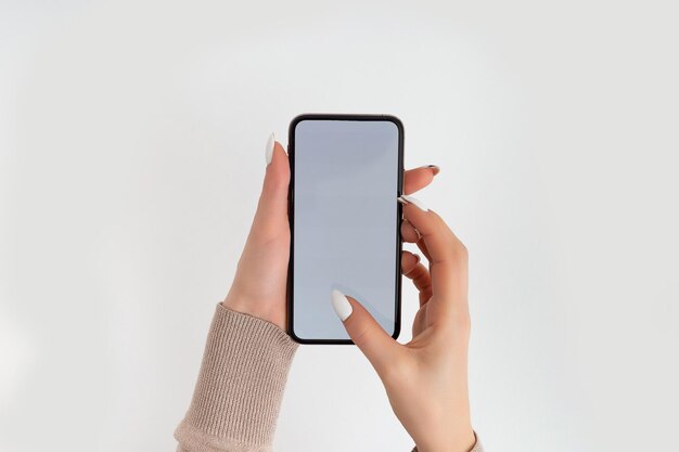 Mano femminile che tiene e tocca lo smartphone mobile con schermo bianco isolato su bianco modello di foto per qualsiasi immagine sul display del telefono cellulare layout con sfondo del monitor del telefono facilmente rimovibile