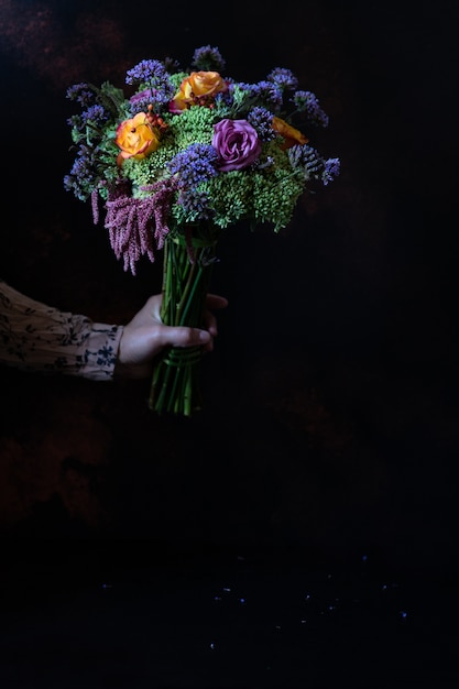 Female hand holding a vintage bouquet of beautiful autumn flowers