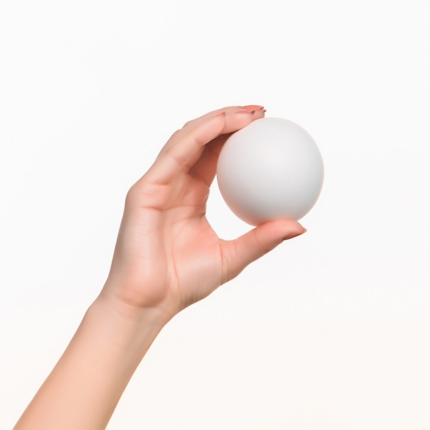 The female hand holding white blank styrofoam ball against the white background.