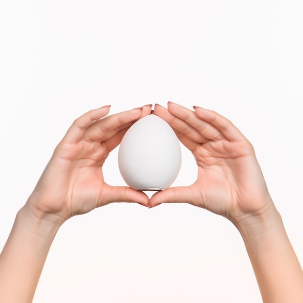 The female hand holding white blank styrofoam oval against the white background  with right shadow