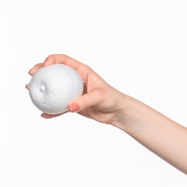 The female hand holding white blank styrofoam oval against the white background  with right shadow