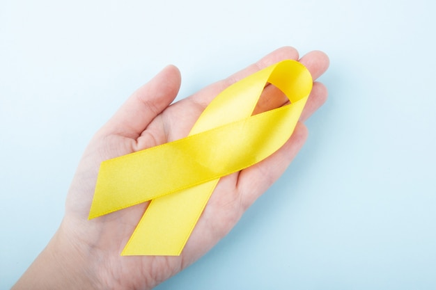 Female hand holding yellow ribbon